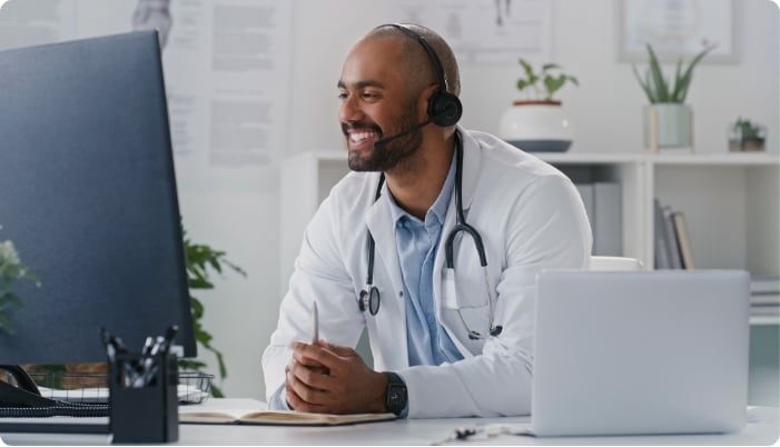 A medical professional smiling and talking with a headset.