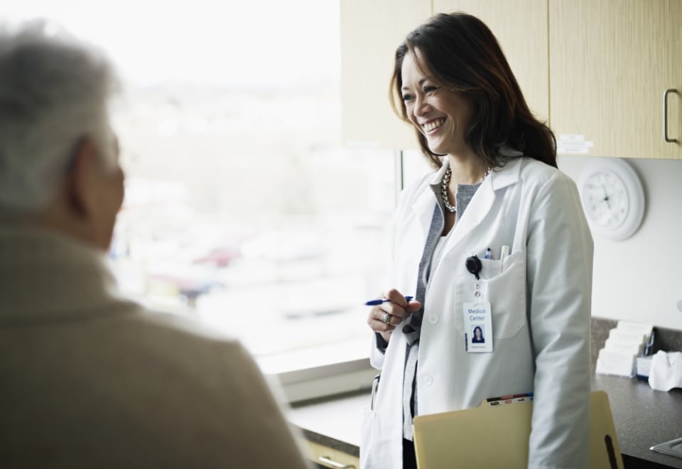 A doctor smiling while talking with a patient.