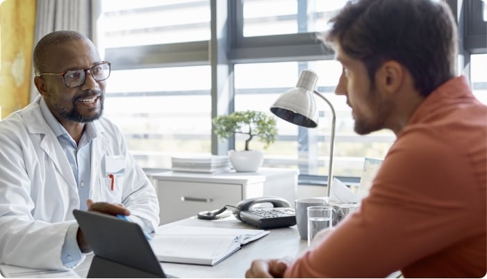 A doctor talking with a patient at a desk.