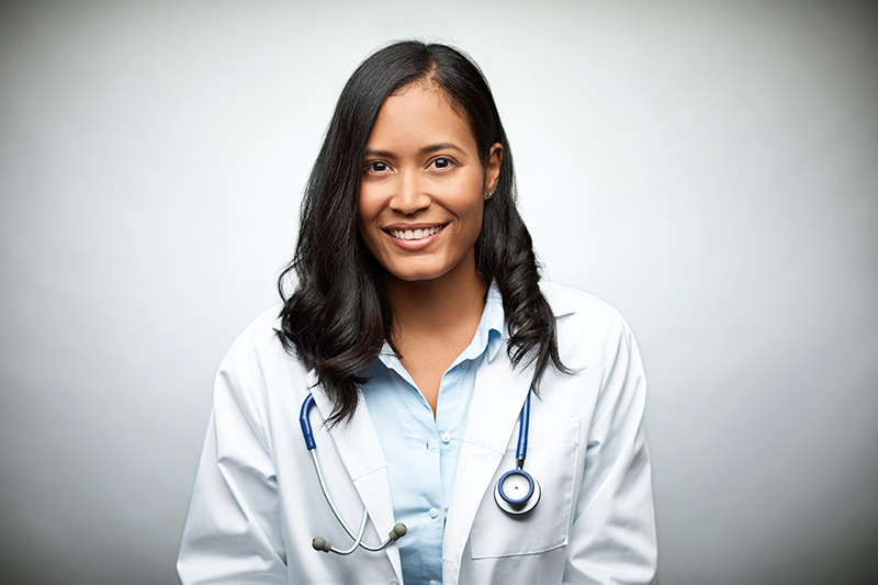 A doctor in a medical coat smiling at the camera.