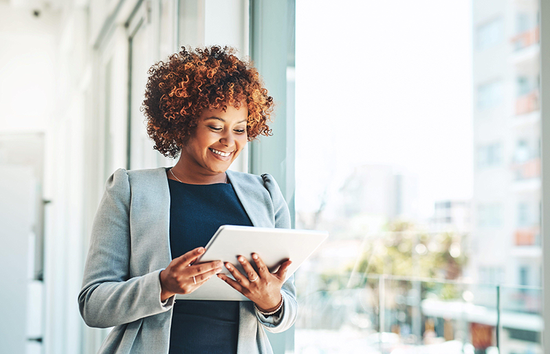 A professional woman reading on a tablet in an office.