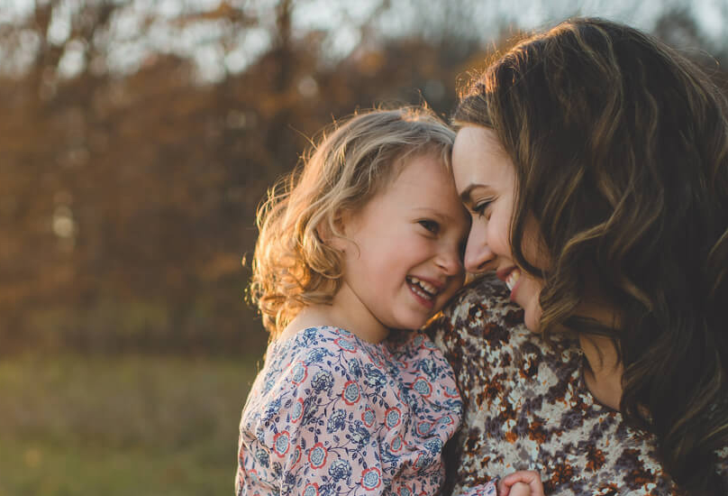 A mother touches her forehead to her toddler.